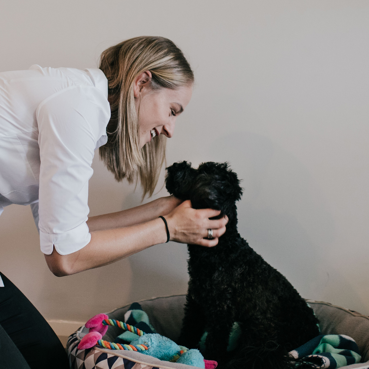 Woman cuddles a black Cavoodle